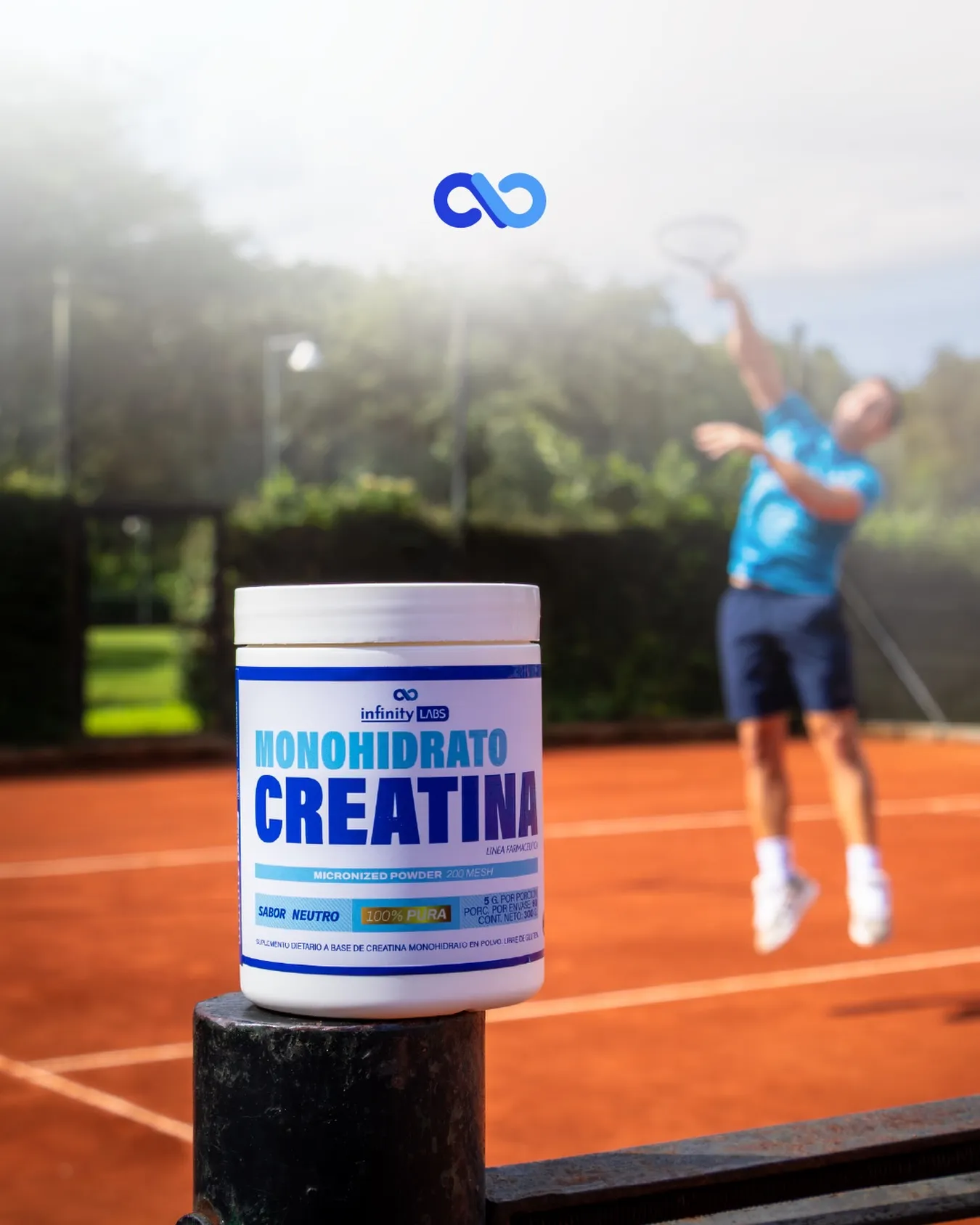 Bote de Monohidrato de Creatina Infinity Labs en primer plano, con un tenista jugando al fondo en una cancha de polvo de ladrillo