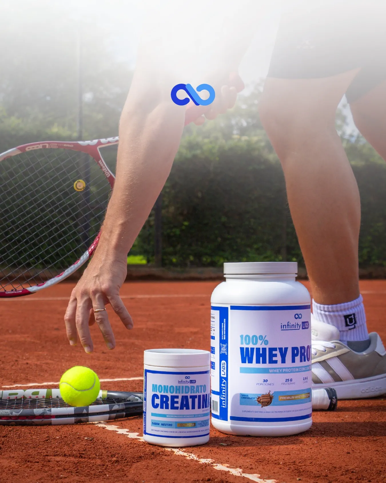 Botes de Creatina y Whey de Infinity Labs sobre una cancha de tenis, con un jugador en acción al fondo